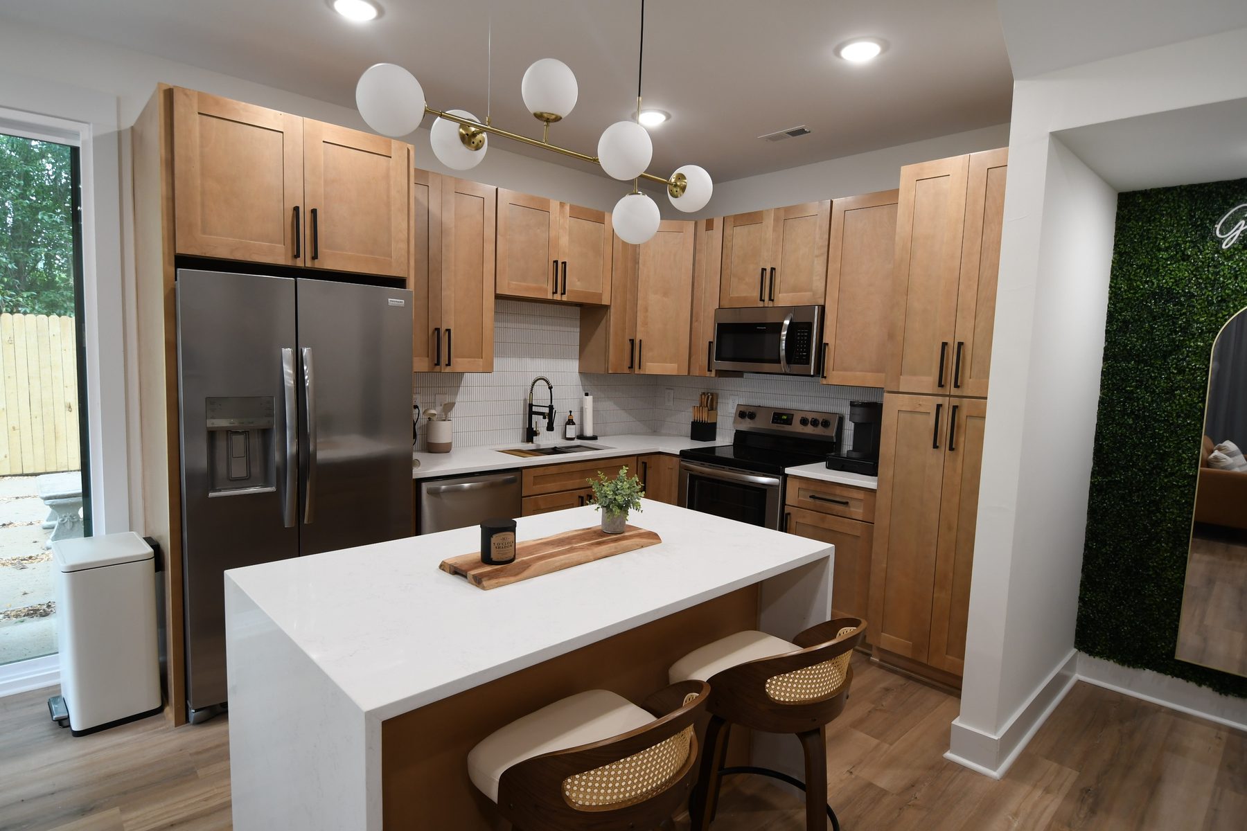 Interior real estate photo of a modern kitchen with maple cabinets, quartz island, and stainless appliances