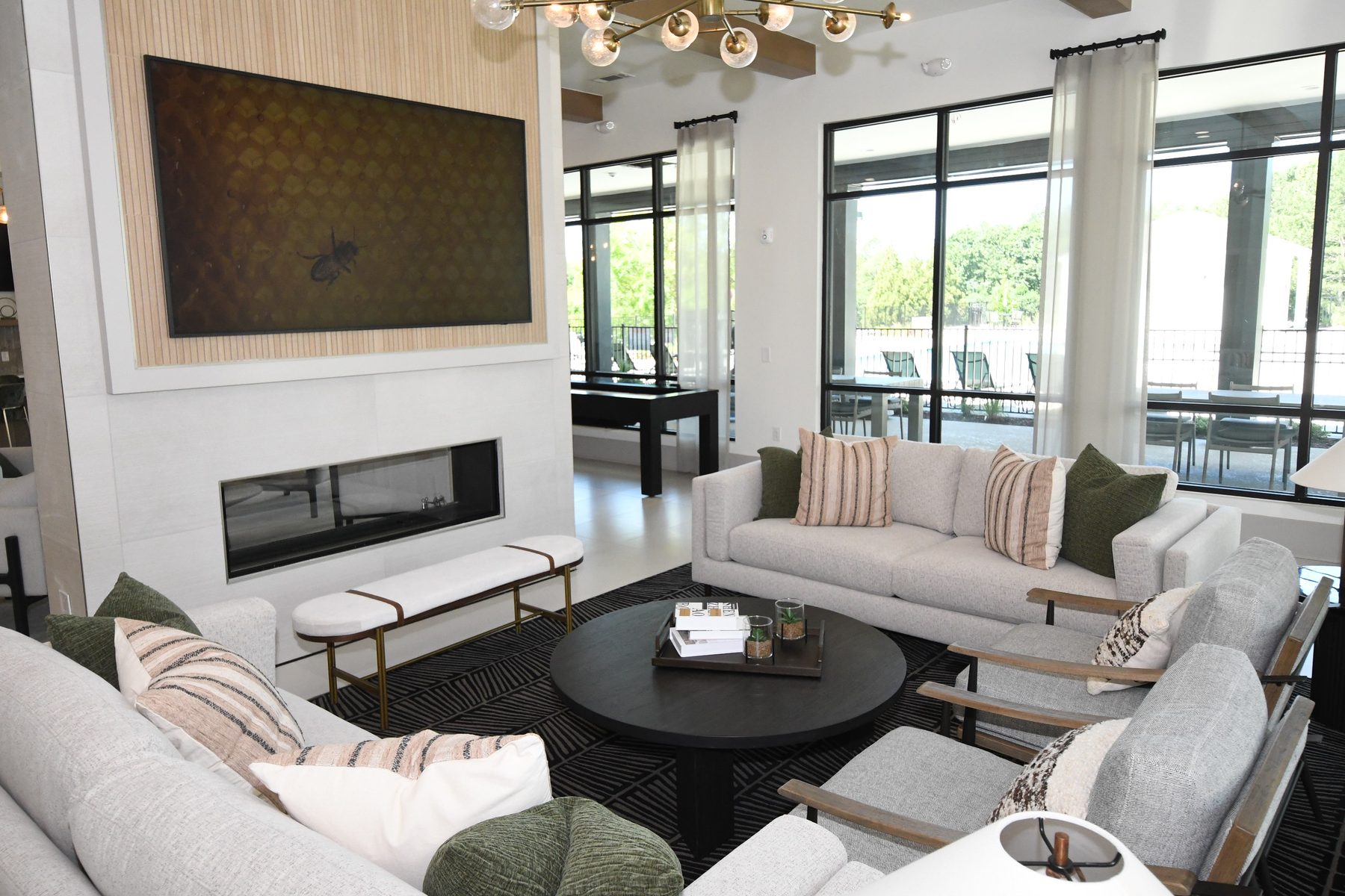 Amenity lounge with linear fireplace, floor-to-ceiling windows, and layered seating